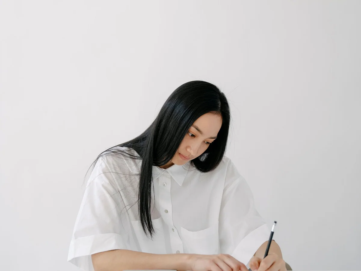 Woman writing and organizing photographs in a creative studio corner